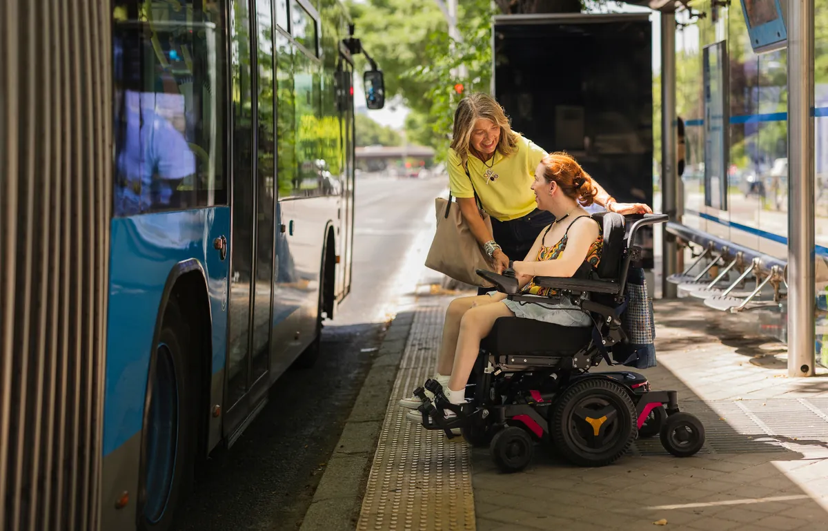 Caregiver assisting a wheelchair user boarding a bus